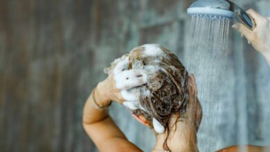 Back view of a woman washing her hair with a shampoo in bathroom.